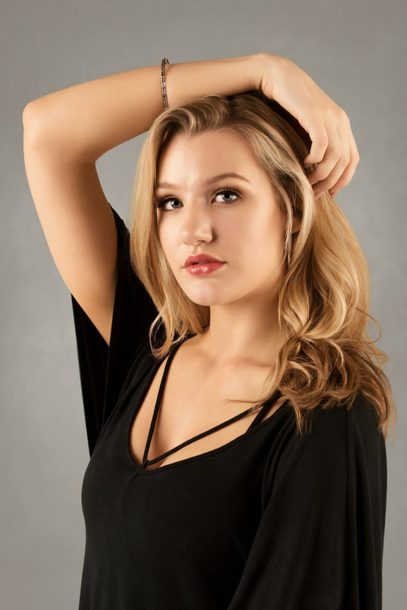 Woman with blonde hair and a black blouse posing in a studio