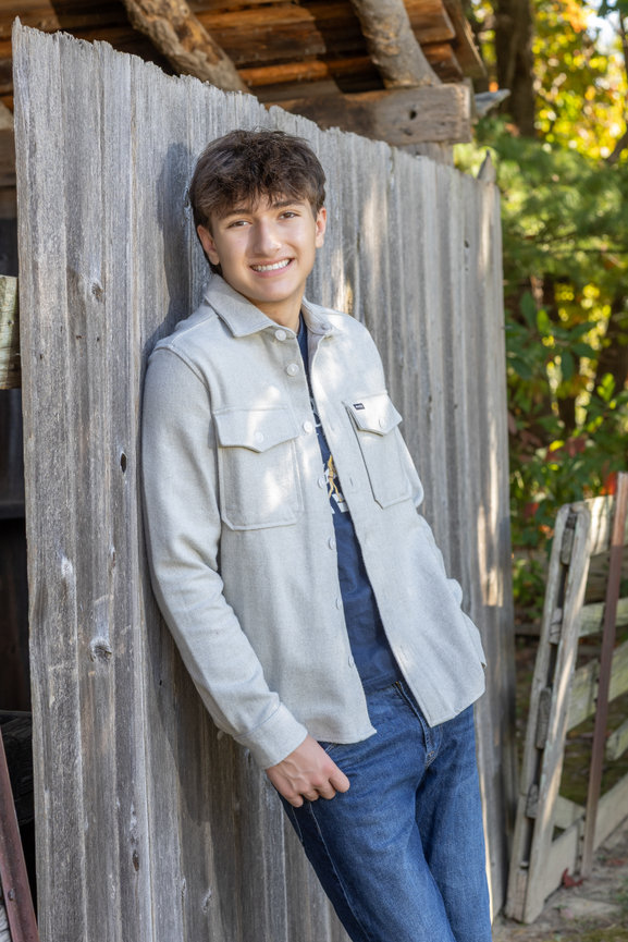 Teen boy leaning against wooden structure