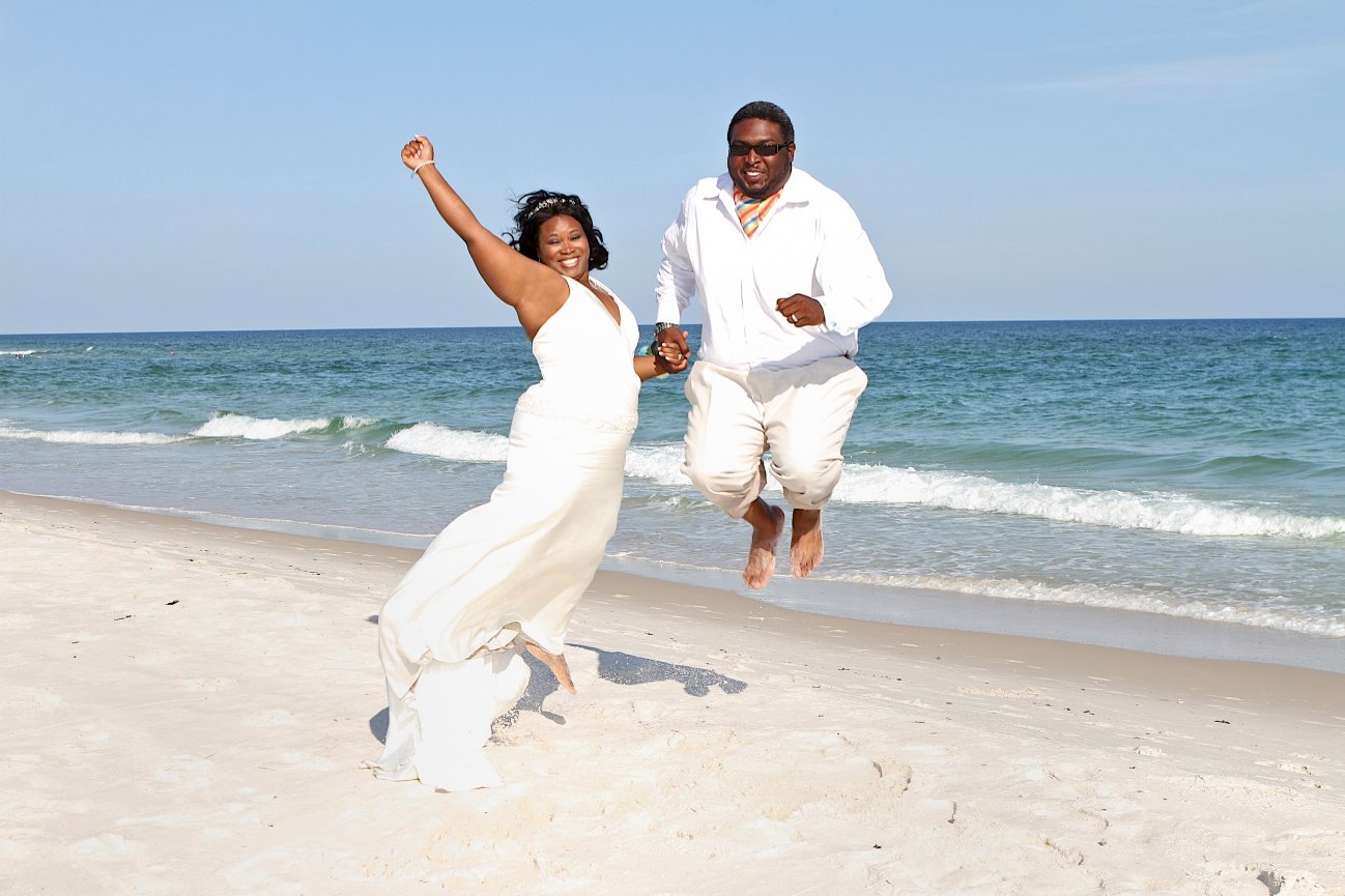 Wedding couple joyfully jumping on the beach