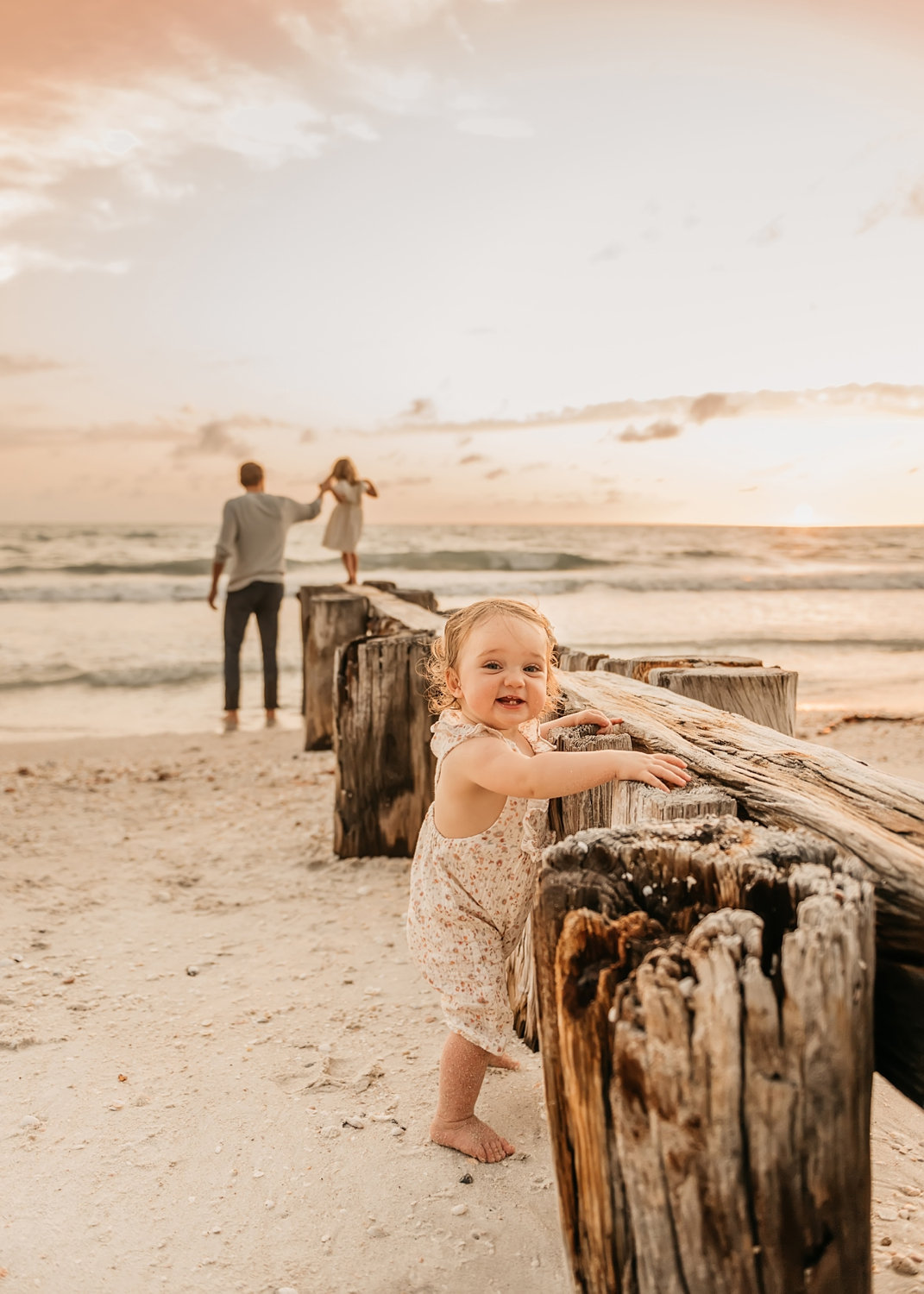 standing baby milestone portrait, father and daughter in background, Ryaphotos