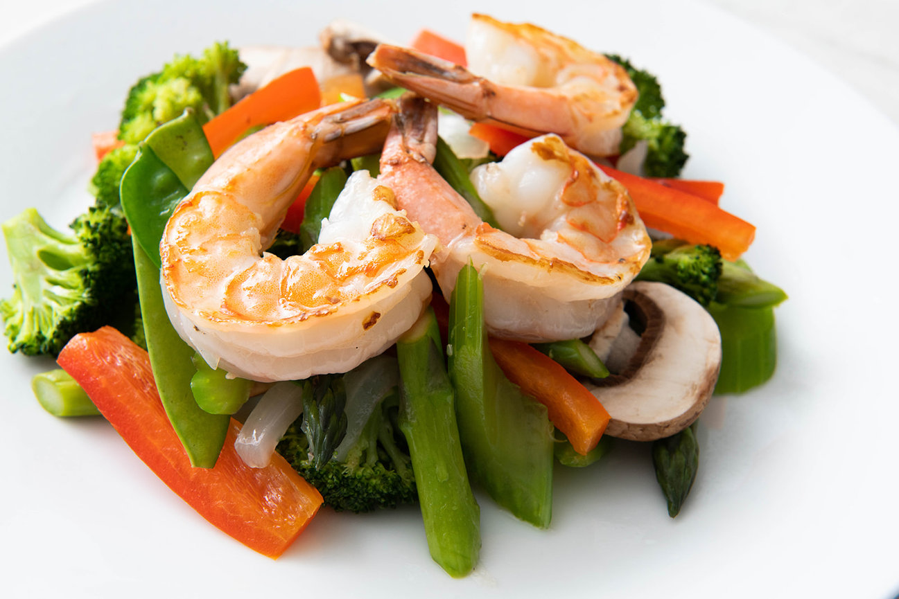 Sautéed shrimp with mixed vegetables including broccoli, bell peppers, and mushrooms on a white plate.