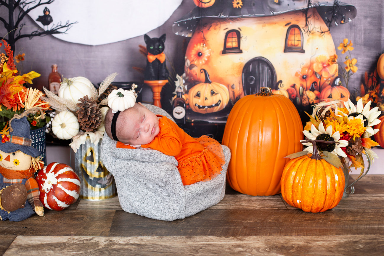 Halloween-themed studio setup with pumpkins, a spooky backdrop, and an orange chair.