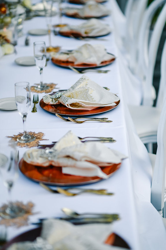 Elegant dining setup with wooden plates, folded napkins, and glassware on a white tablecloth.