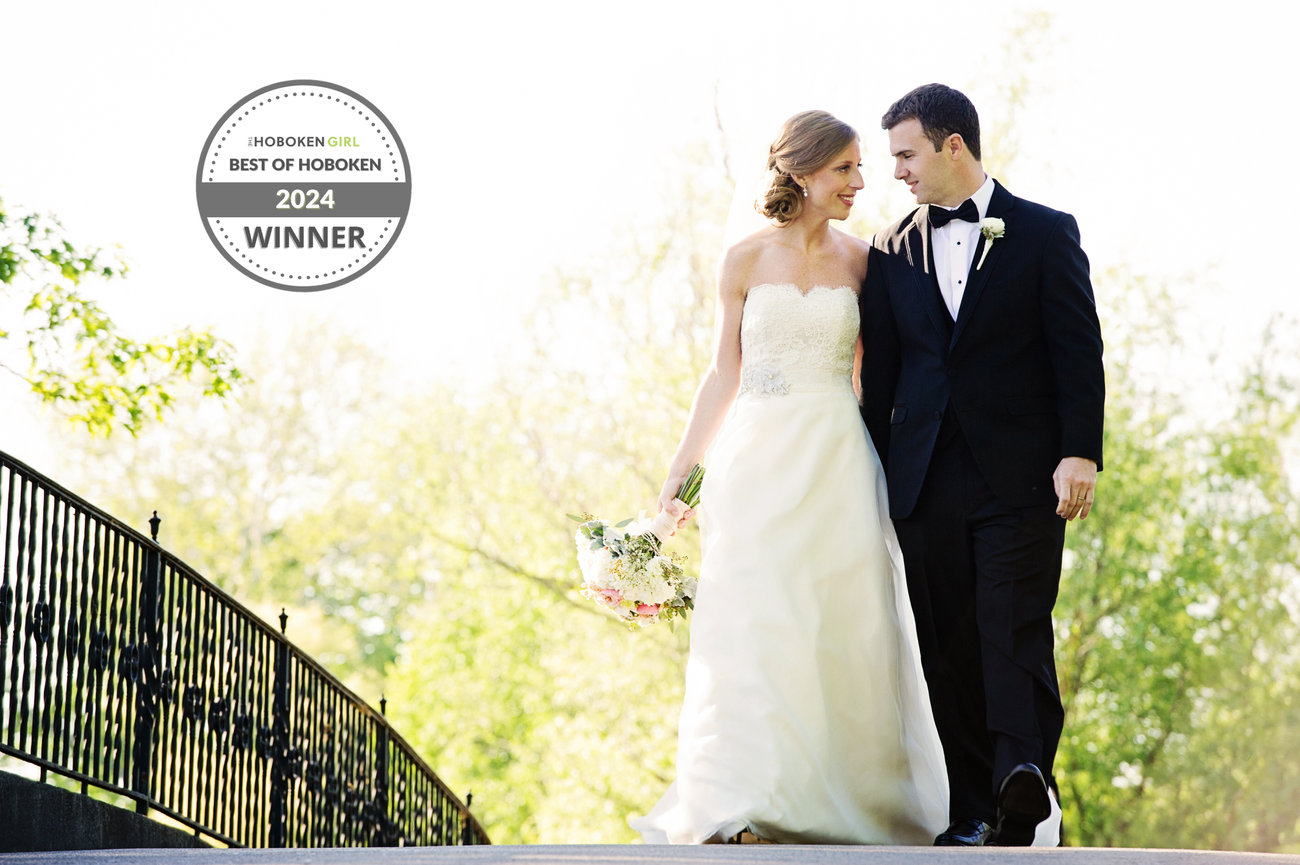 Bride and groom walking across a bridge, surrounded by greenery, with a Best of Hoboken 2024 Winner badge.
