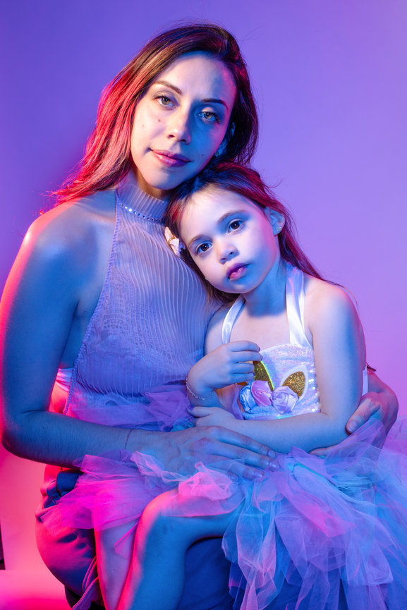 Professional Las Vegas photography studio sessions by Adam Trujillo, featuring artistic portraits and custom hair and makeup. Gorgeous gel lit portraits with Mother and young daughter mixed with subtle blue and purple tones and beautiful pink.