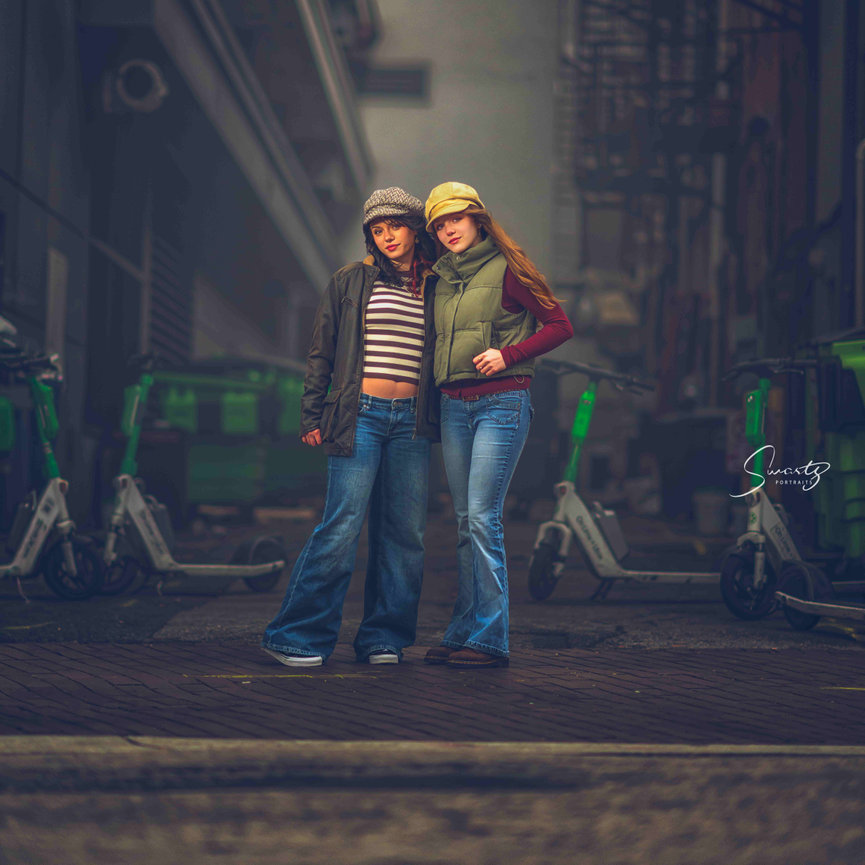 Two sisters posing together in urban setting with professional studio lighting