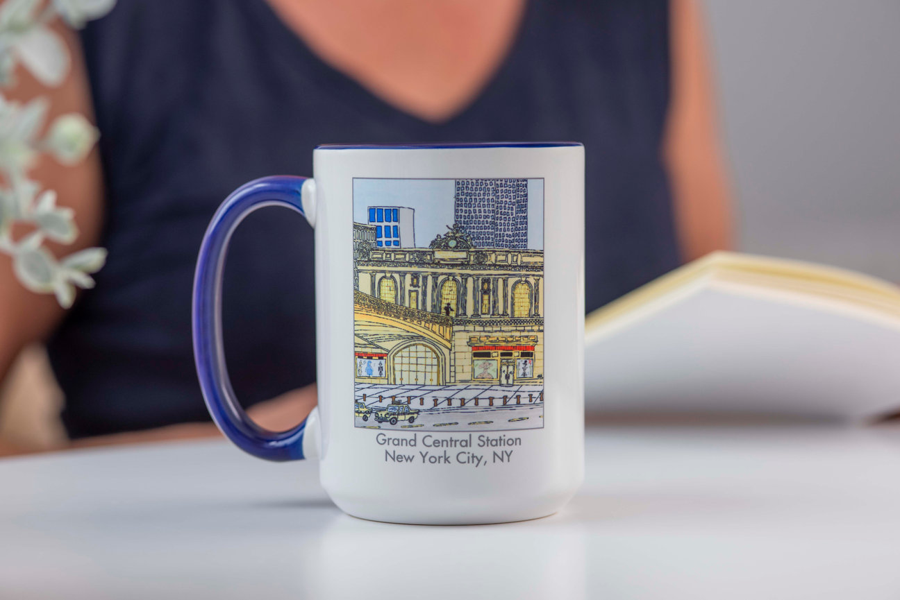 Woman seated at table reading a book with mug in front of her