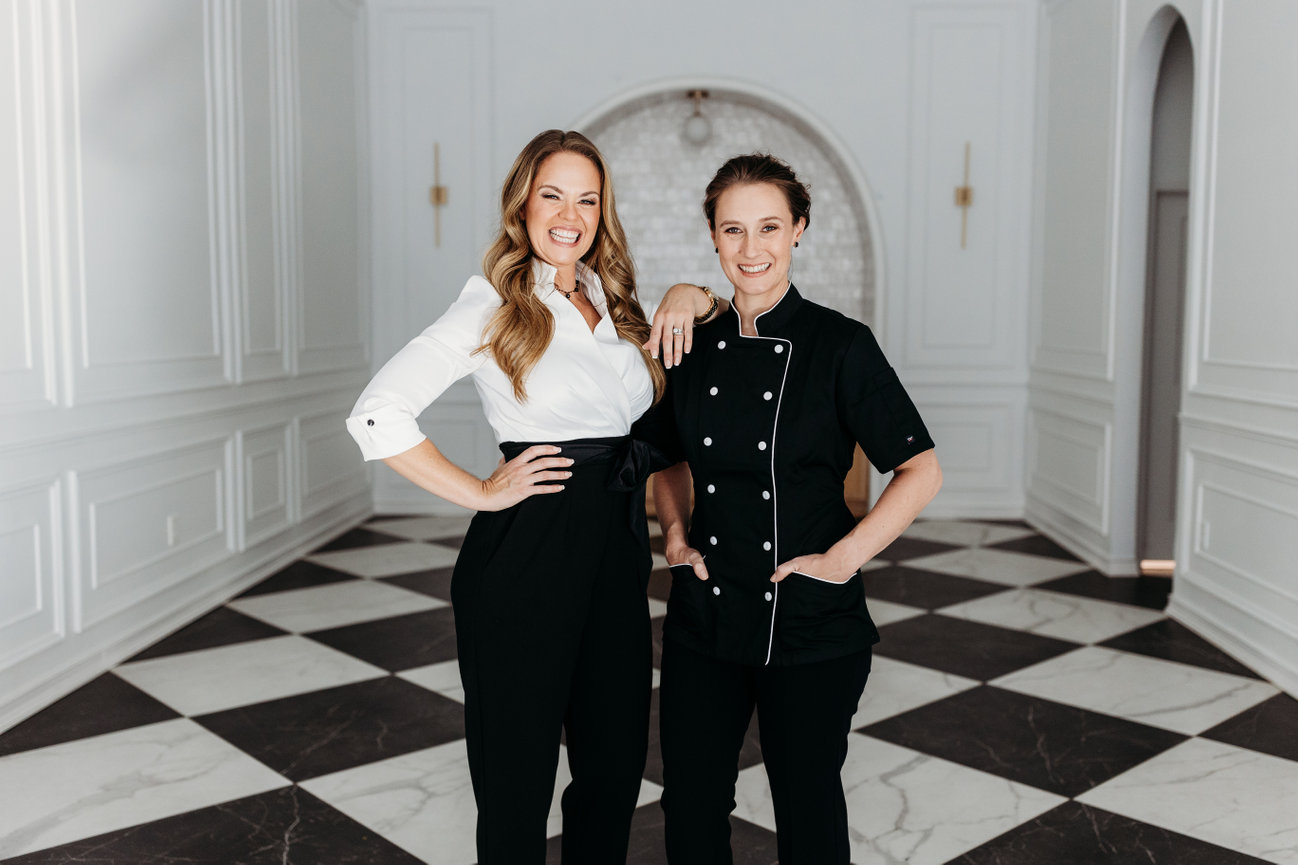 Two women in black and white stand side by side in a black and white hallway