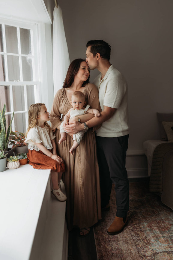 A beautiful family snuggled close by a window in a Mendham, New Jersey photography studio.