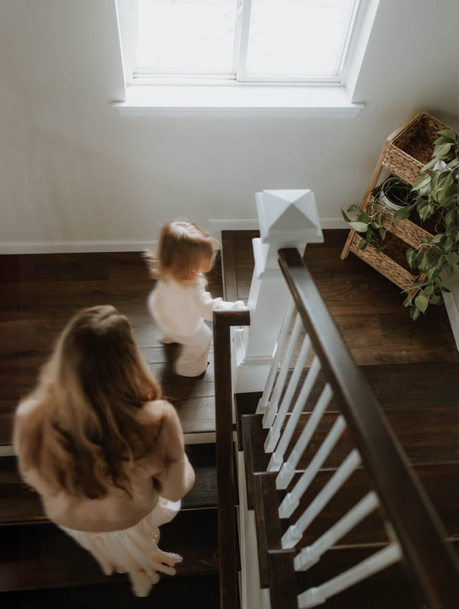 A mother chases her daughter up the stairs during a New Jersey baby photography session.