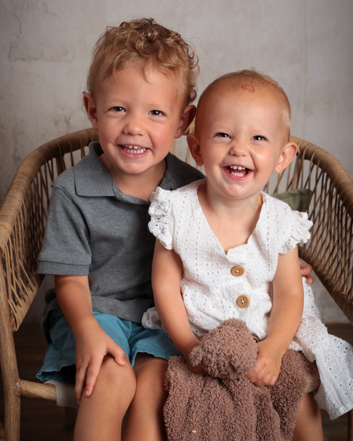 Smiling boy and girl hugging, against a patterned background.