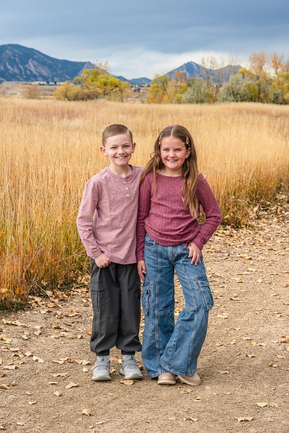 A young brother and sister stand in the dried grasses of the front range.