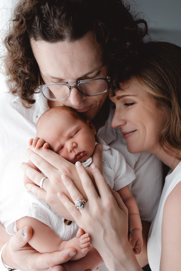 Parents cuddling newborn baby in a tender family portrait