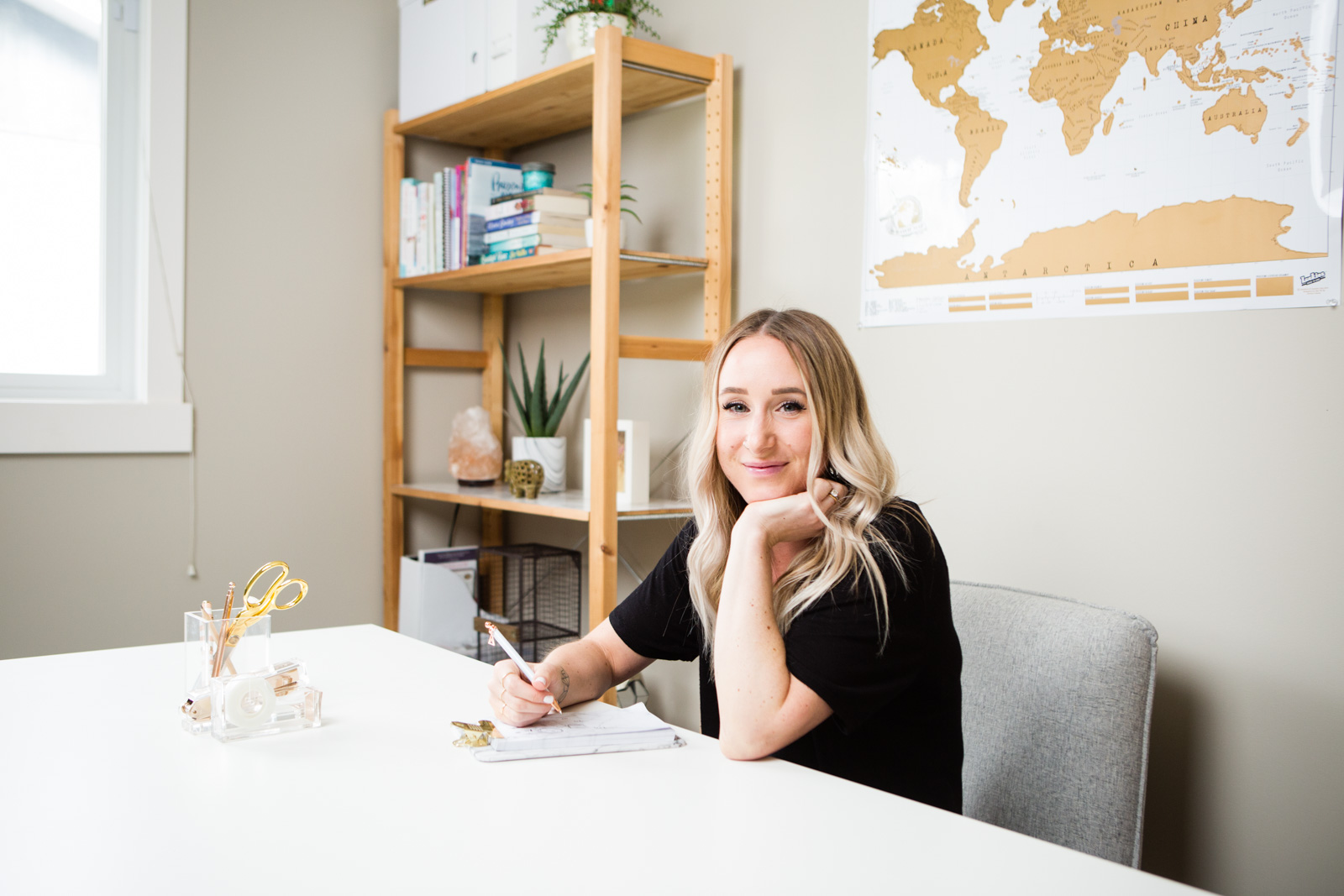 A personal brand lifestyle photo of a woman sitting at her office desk smiling