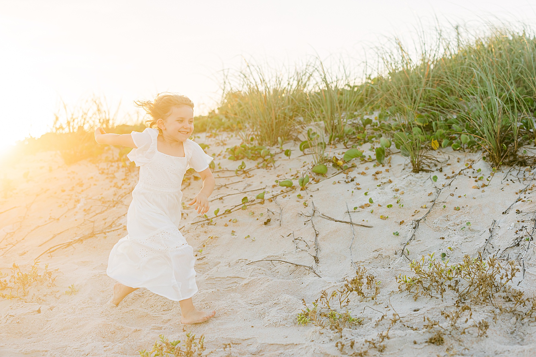 little girl running on the beach in white dress