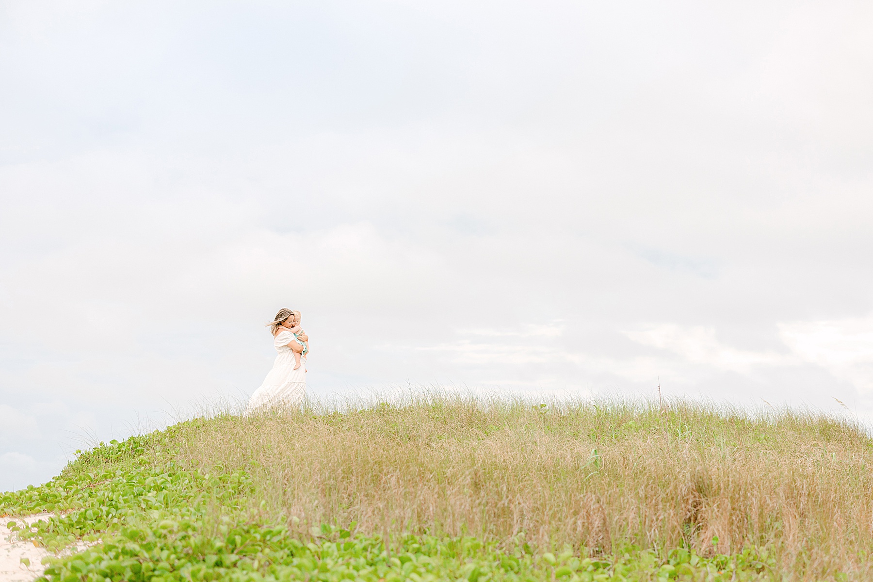 woman in white dress standing on grassy beach