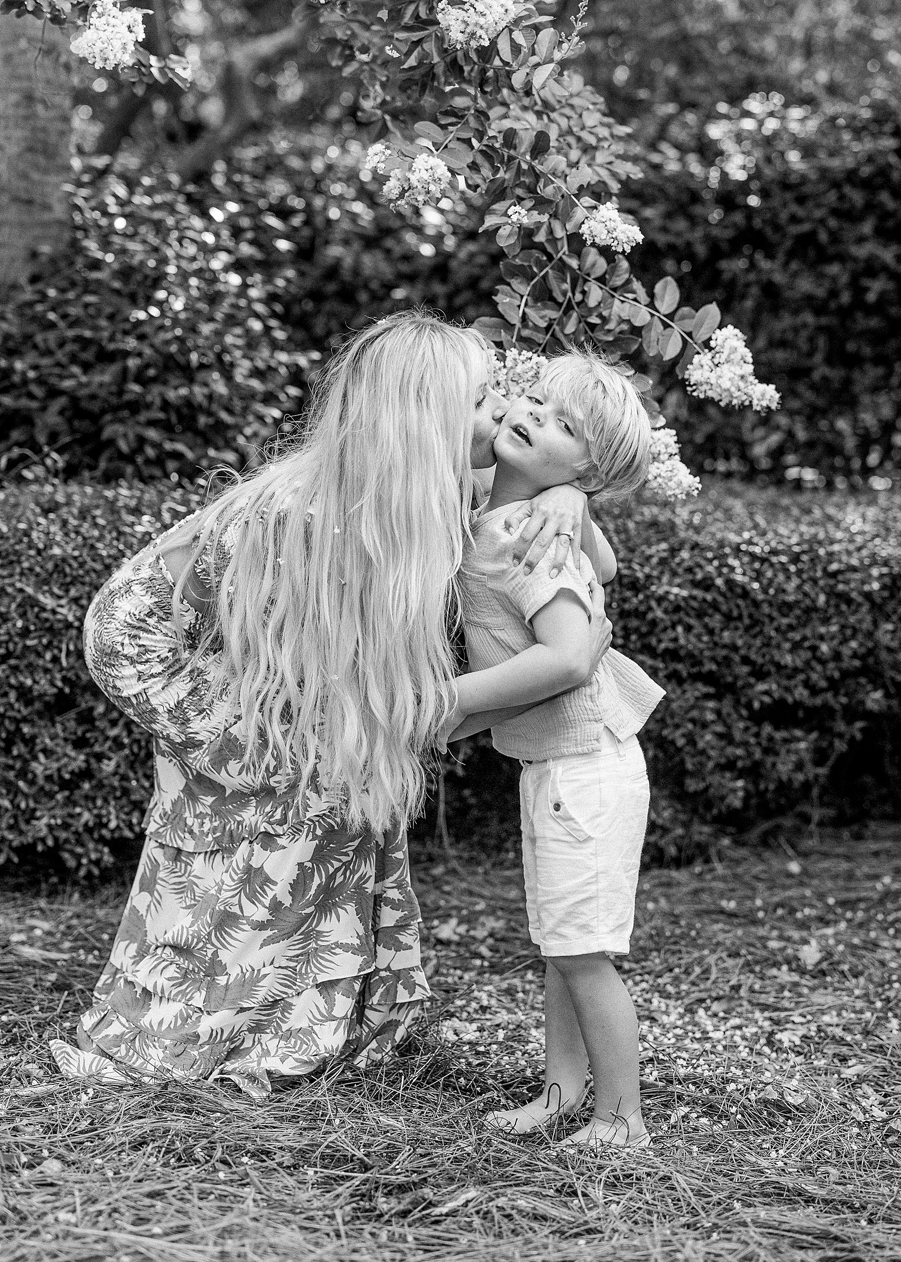 woman kissing little boy in flowers barefoot