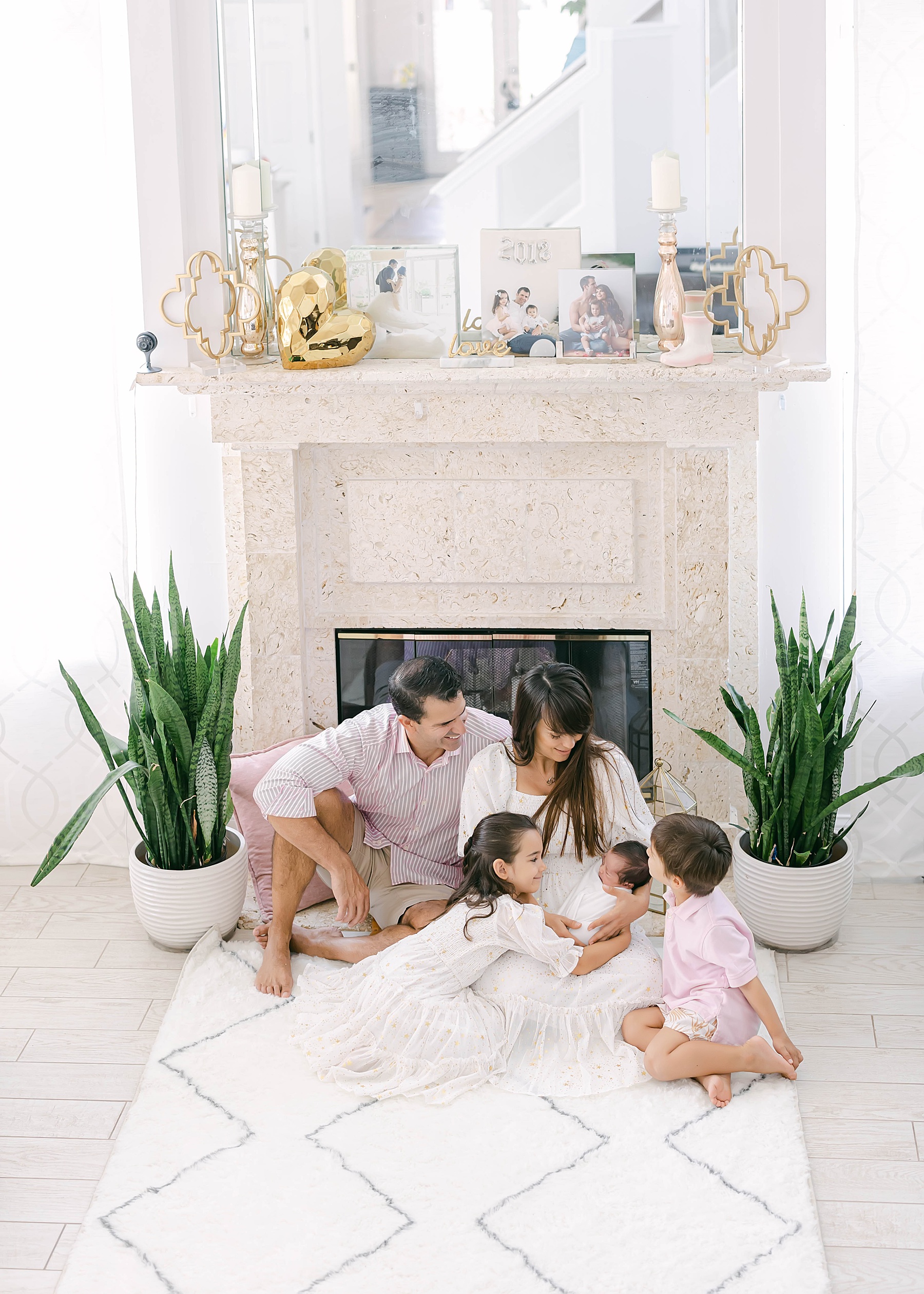 family sitting on carpet holding little baby