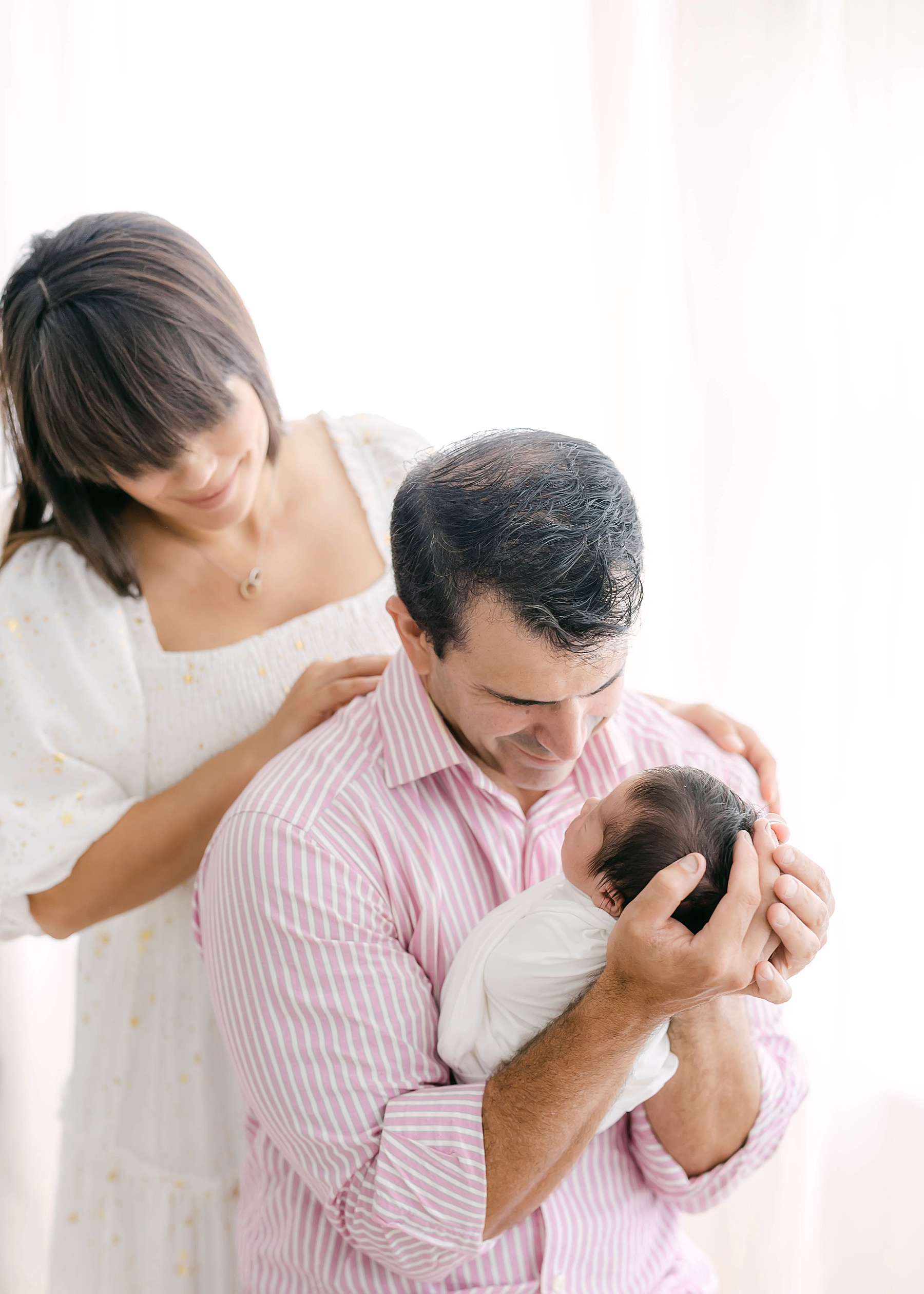 mom and dad holding newborn baby on chair
