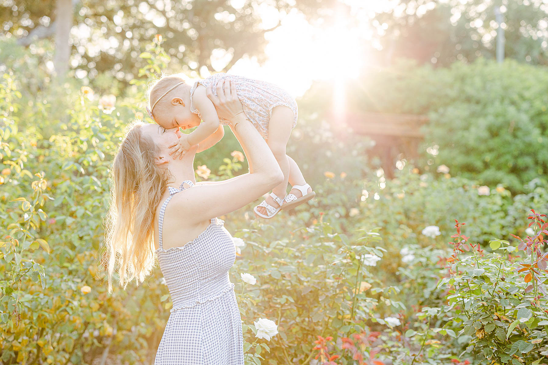 woman holding baby girl in the garden with sunlight 