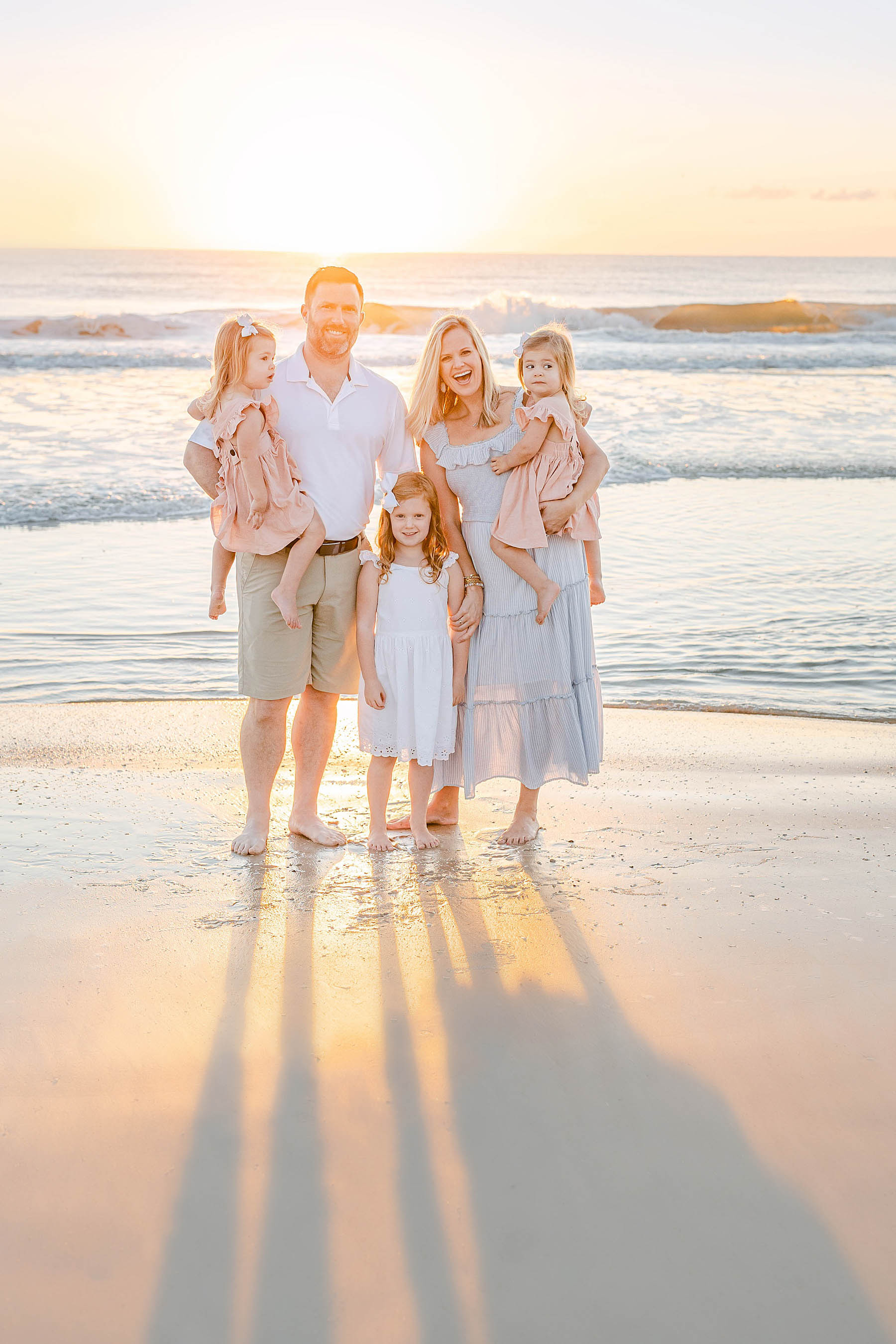 family standing together on the beach at sunrise