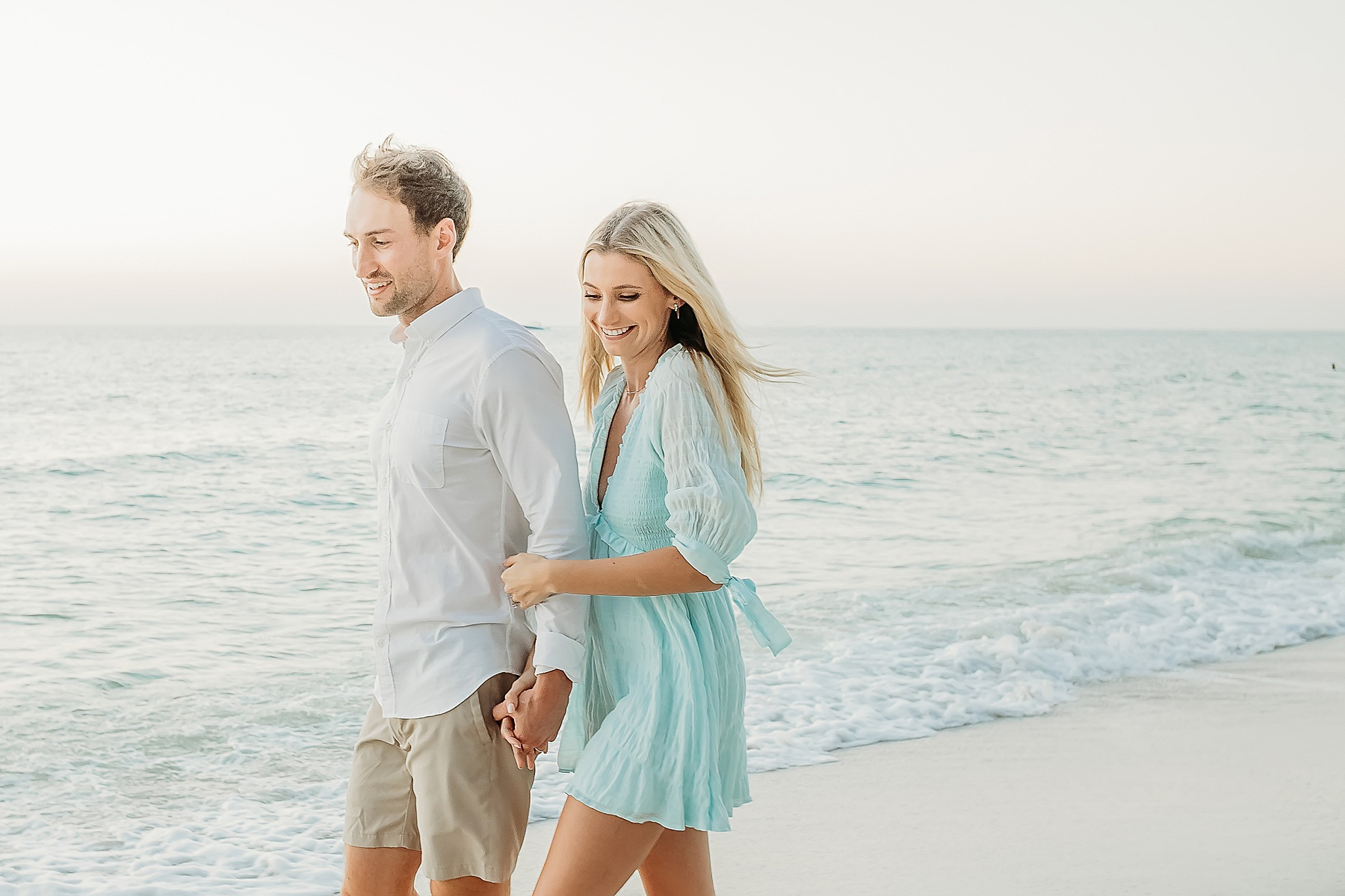couple walking on the beach wearing blue and white