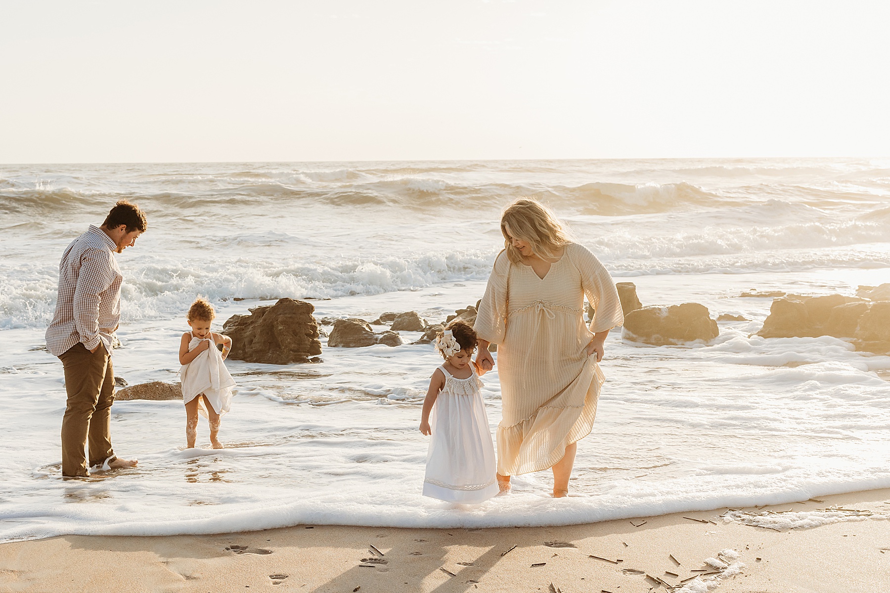 family walking together wearing neutral colors on the beach at sunrise