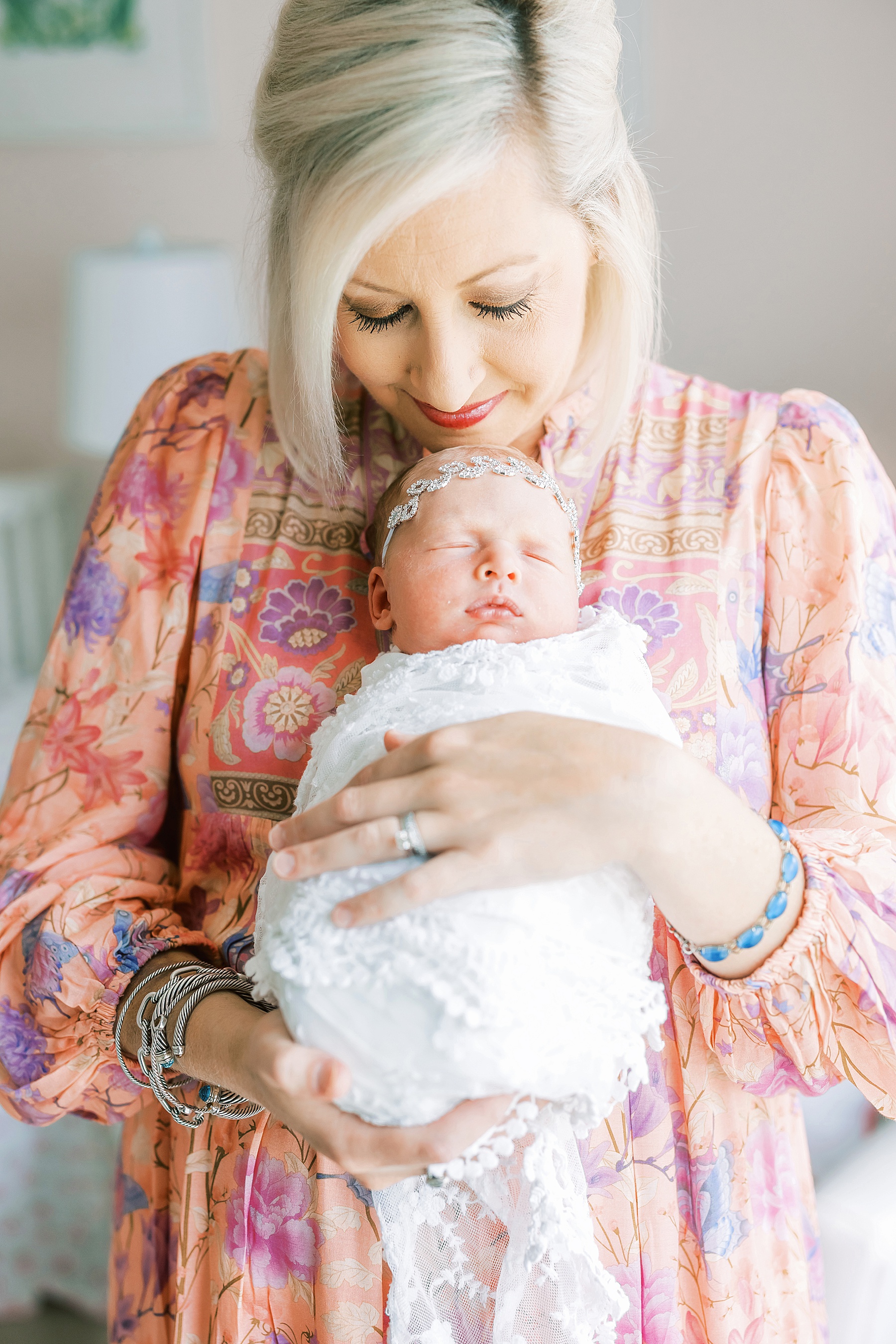 woman holding newborn baby girl wrapped in white wrap dressed in pink maxi floral dress