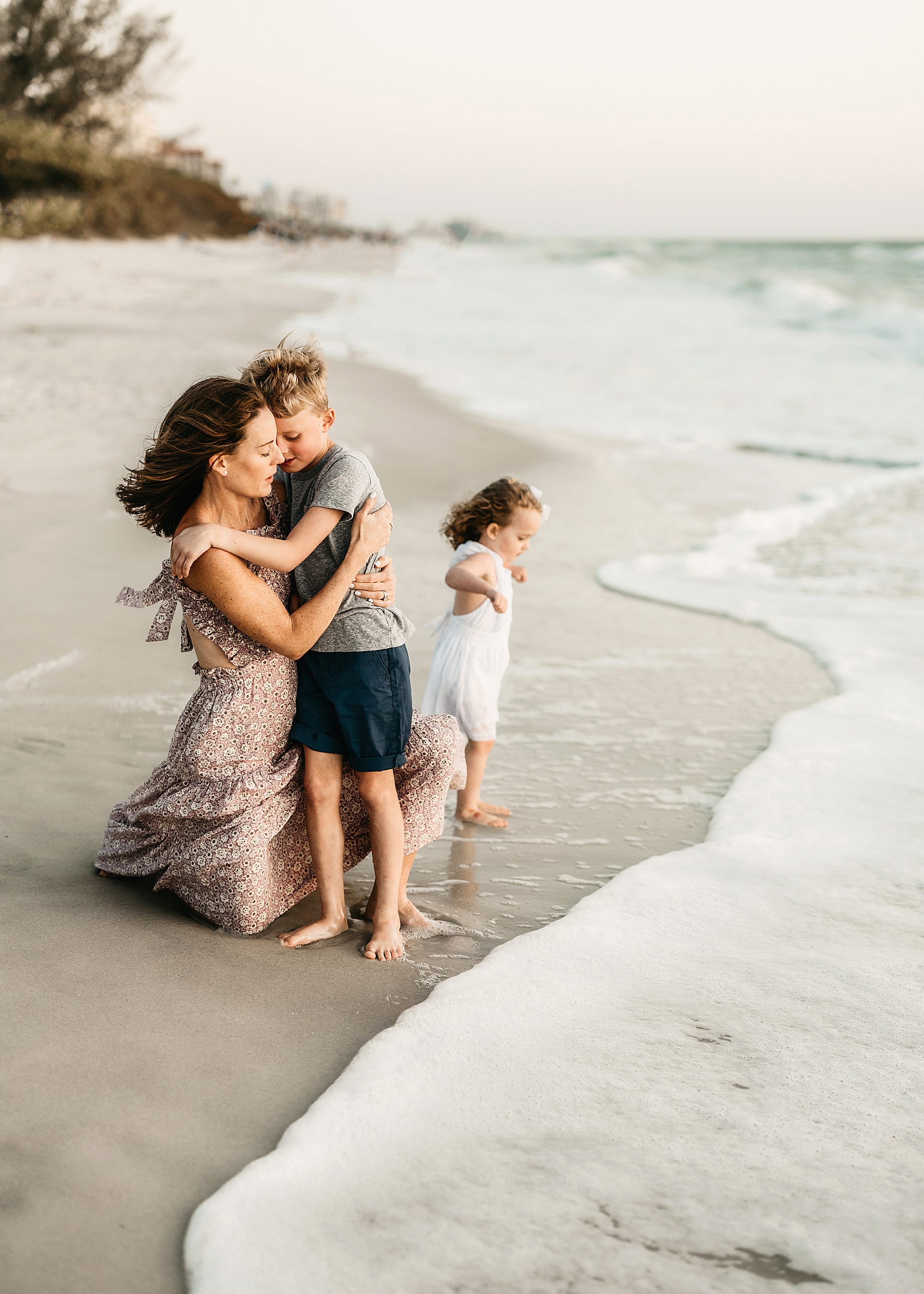 woman holding little boy at sunset on the beach in Naples at Wiggins Pass