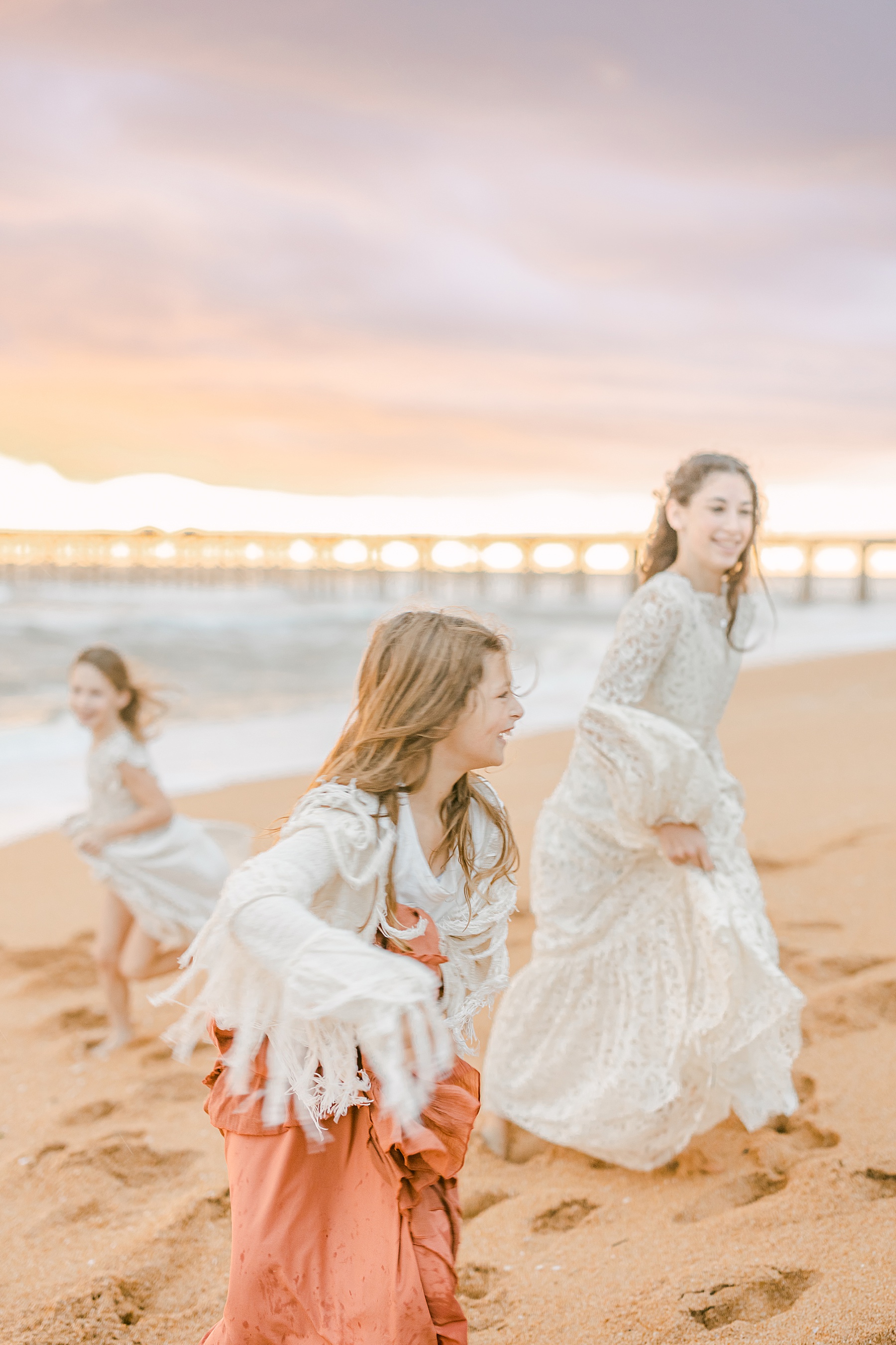 sisters dancing in the sand at flagler pier at sunrise
