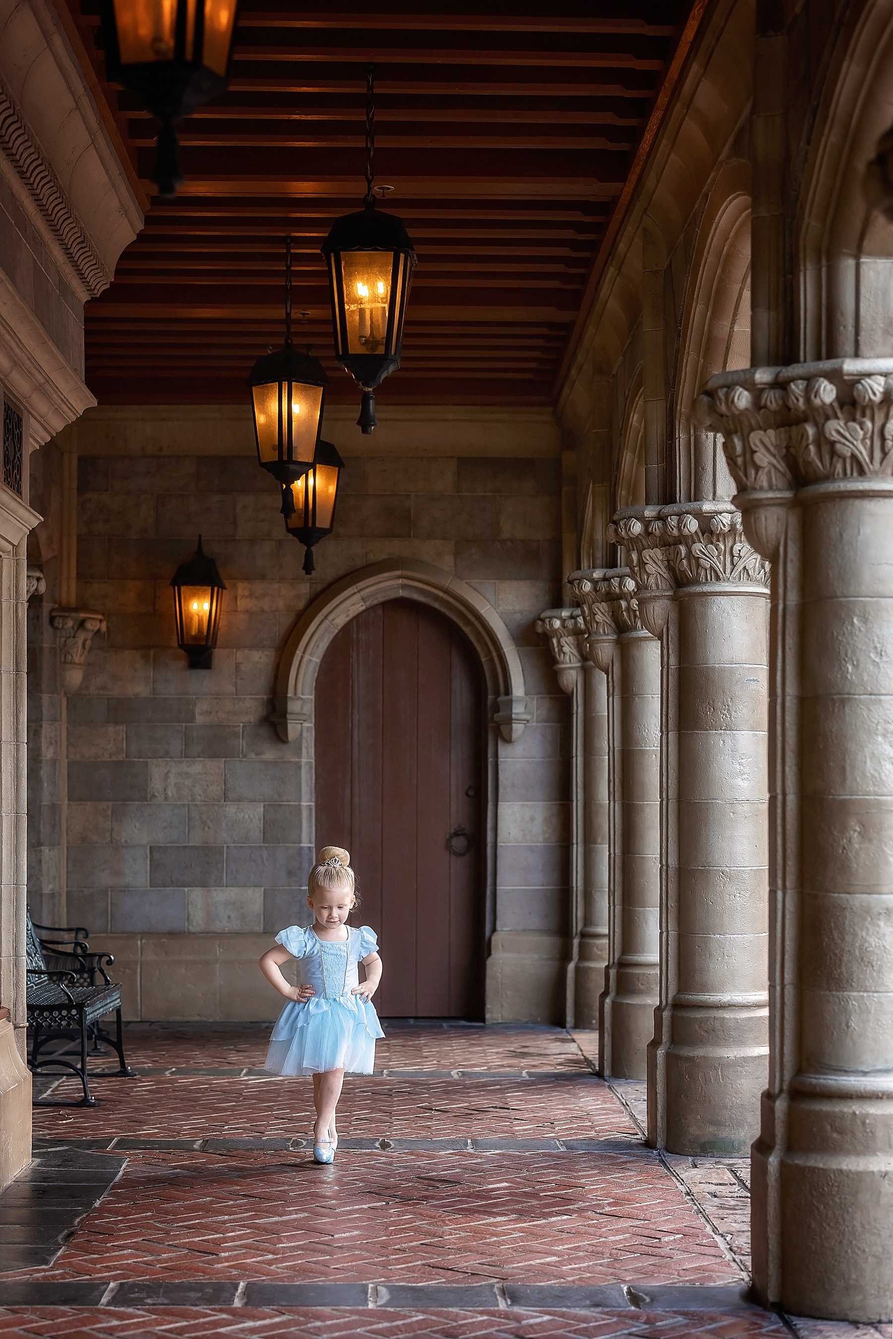little girl with blond hair in blue Cinderella dress by castle