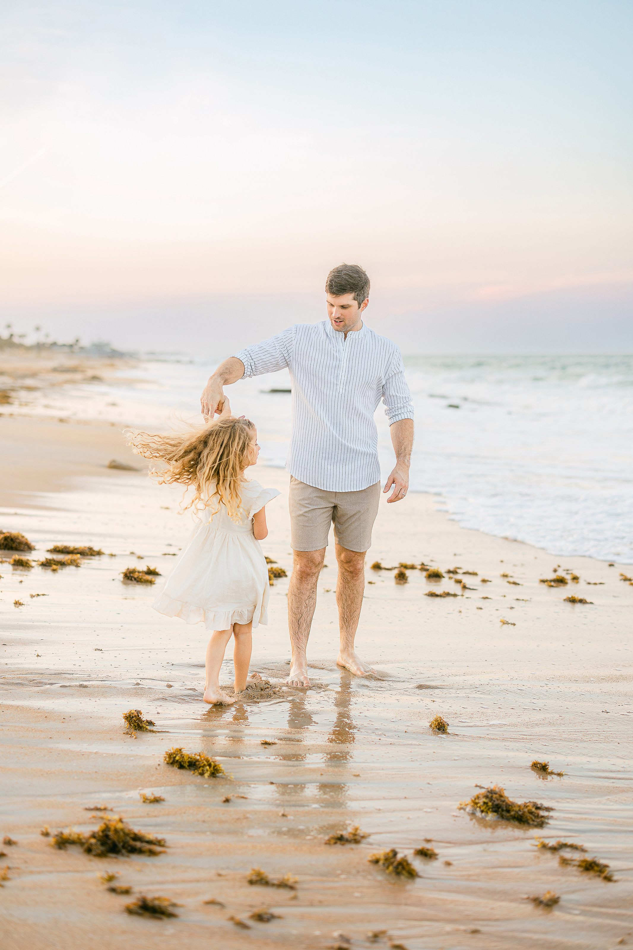 man twirling little girl at sunset on the beach in St. Augustine Florida