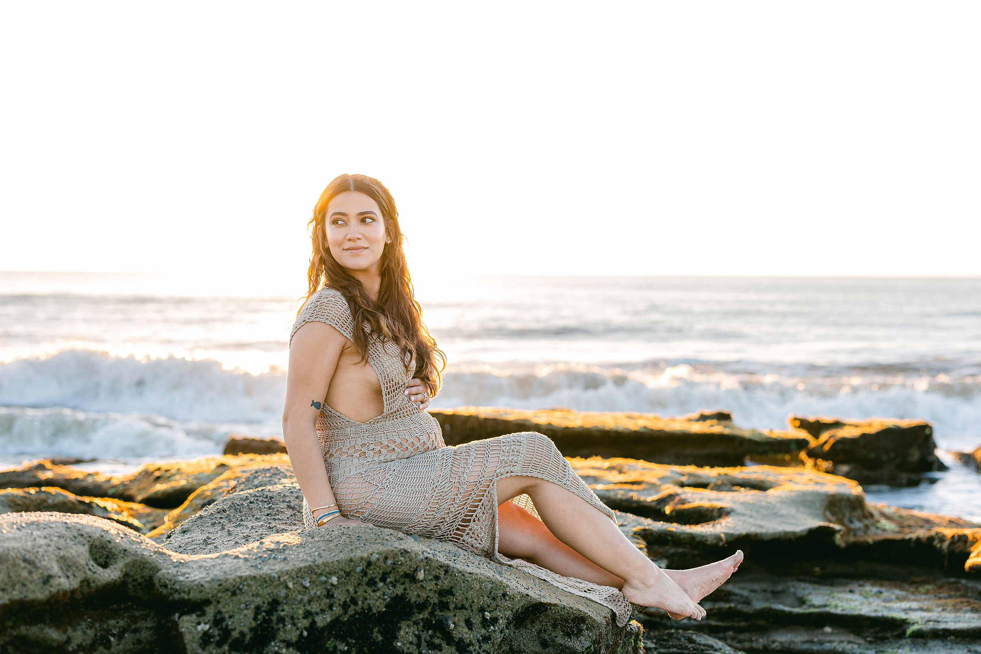 maternity portrait of woman on the beach in fishnet dress at sunrise