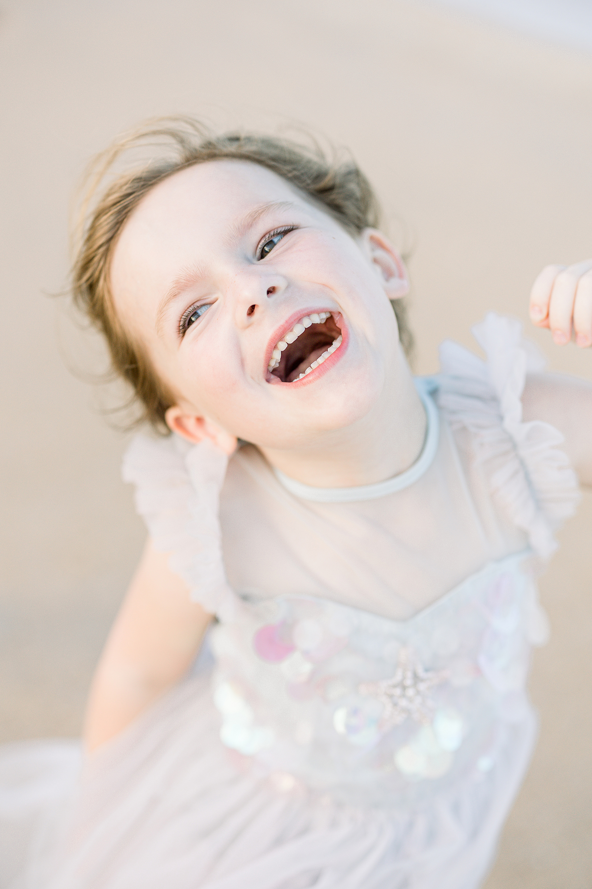 little girl laughing in pastel dress on the beach