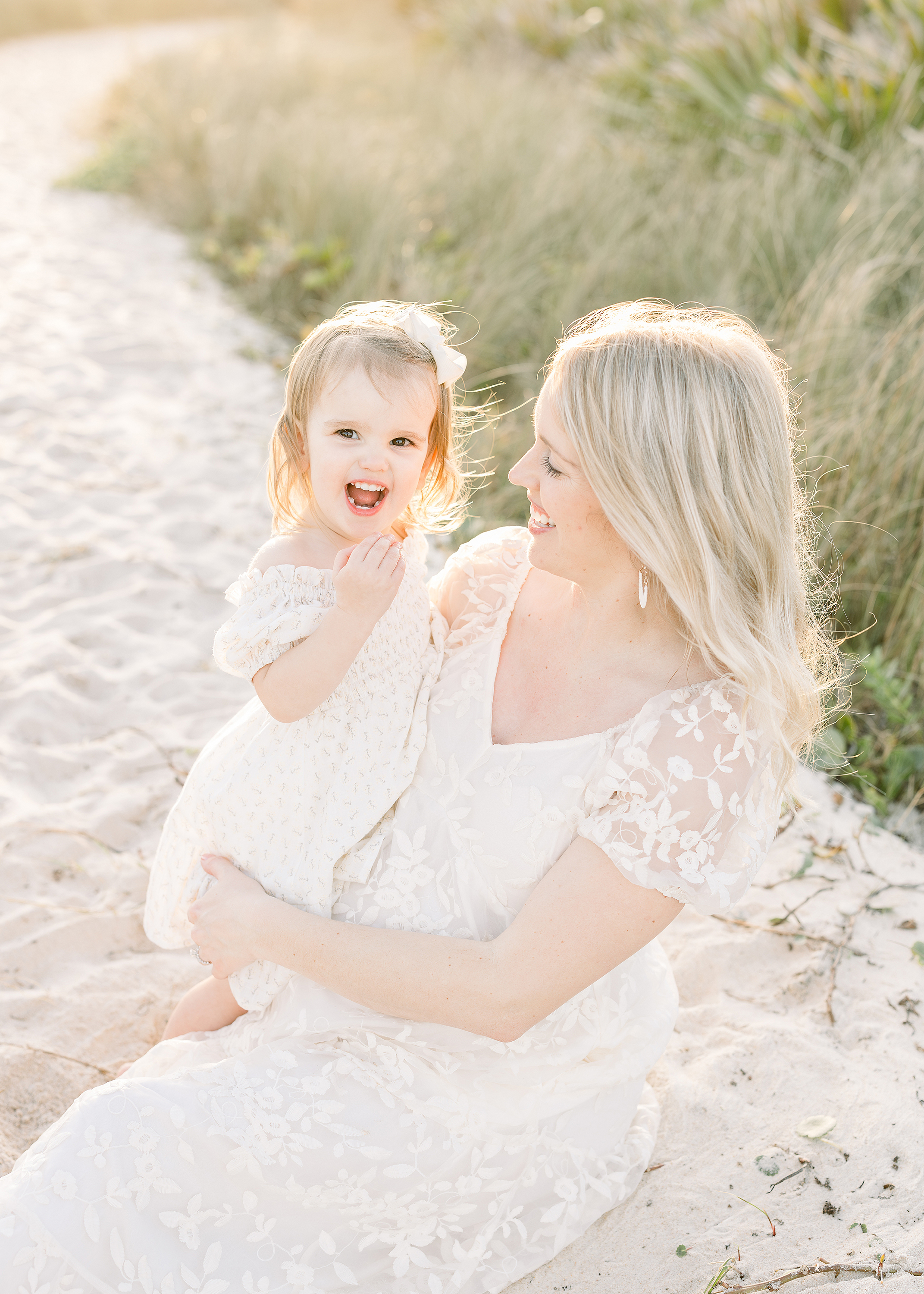 A light and airy sunset motherhood portrait of a pregnant woman and her toddler child.