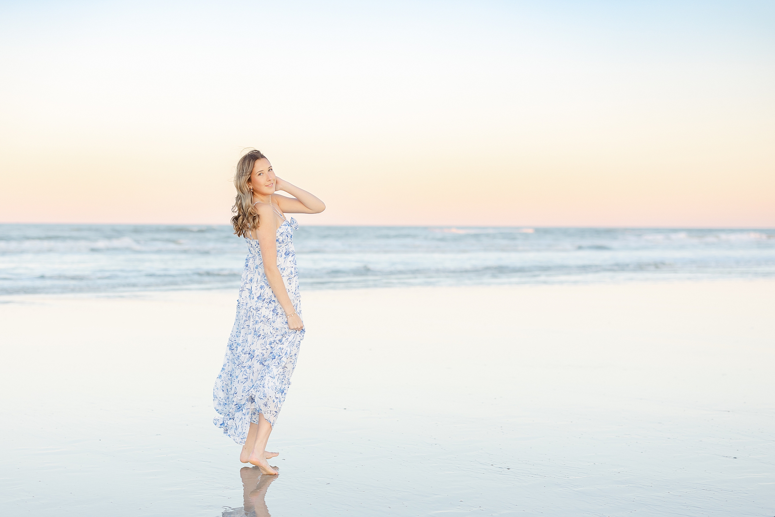 A soft sunset portrait of a young woman running towards the water on St. Augustine Beach.