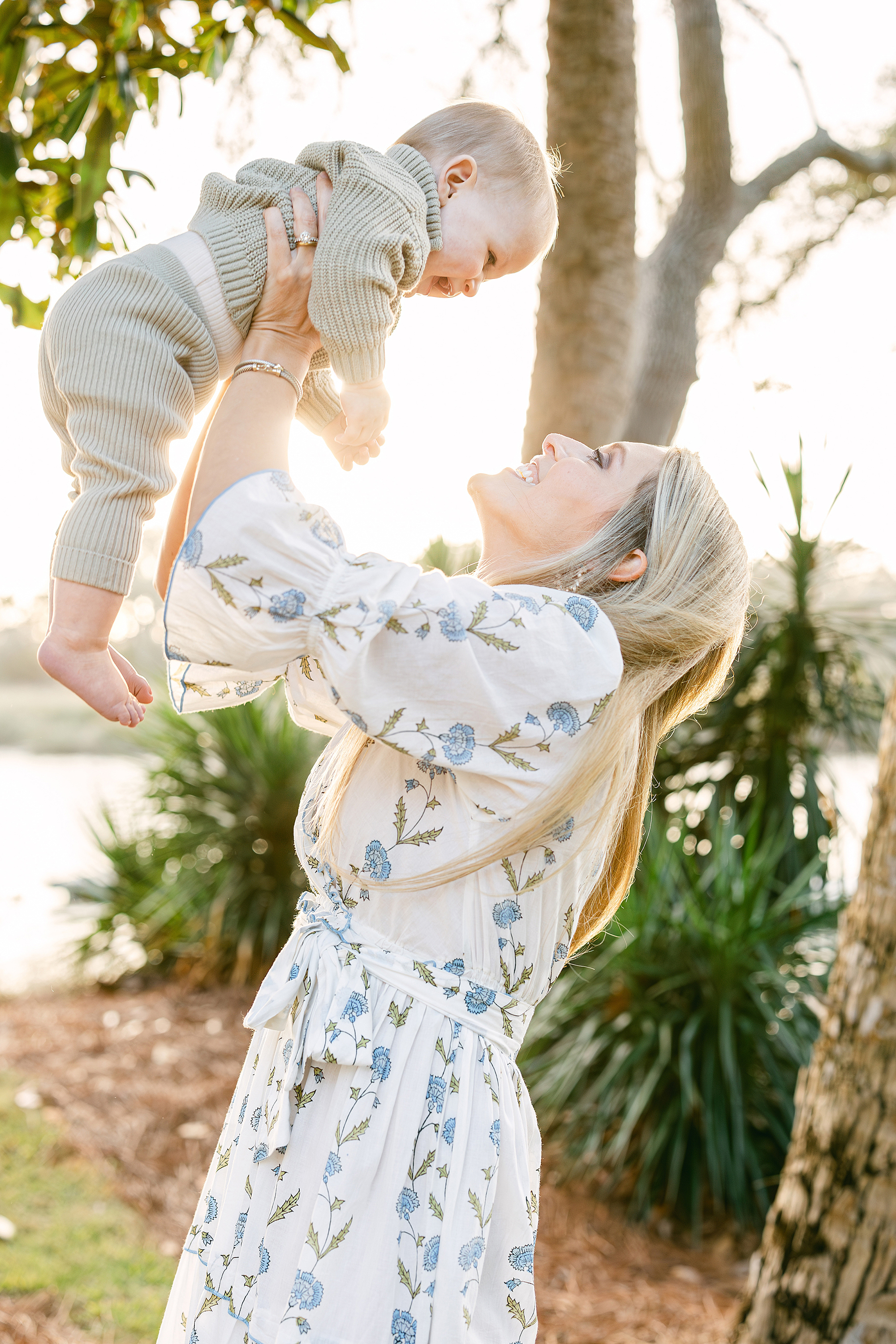 A light and airy portrait of a mother holding her baby boy in the air.