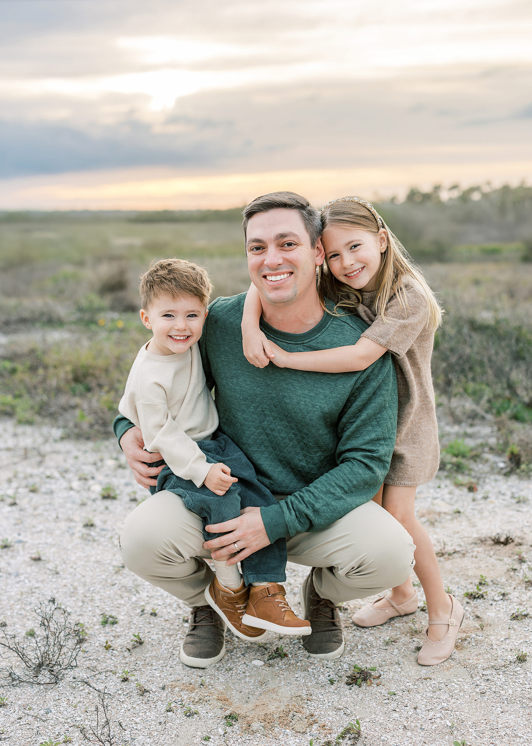 Two children dressed in taupe and hunter green play together at the beach in St. Augustine.