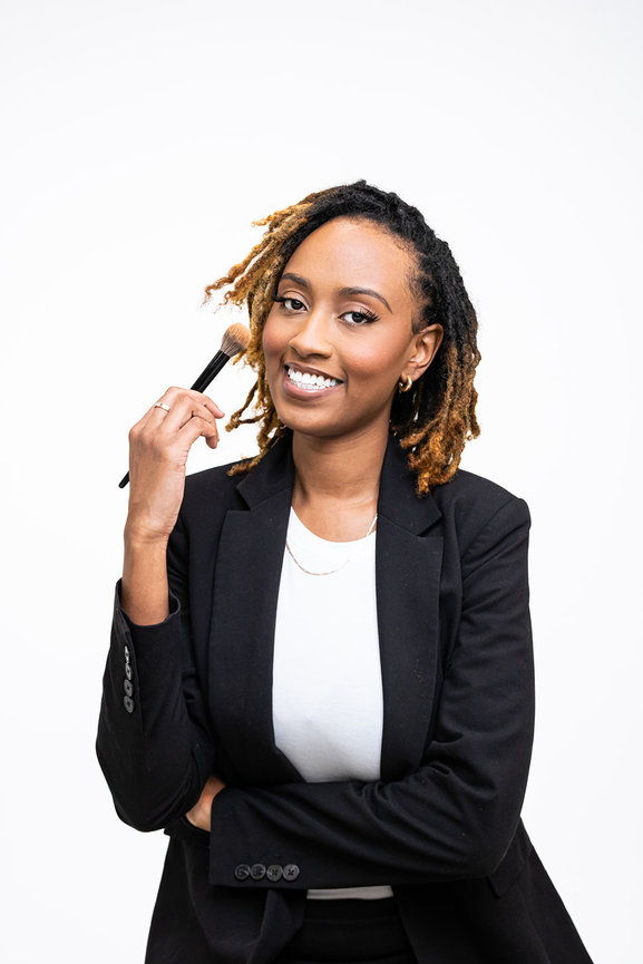 Woman in blazer holding a makeup brush