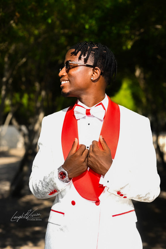A gentleman in a white tuxedo paired with a vibrant red bow tie, showcasing a refined and fashionable appearance.