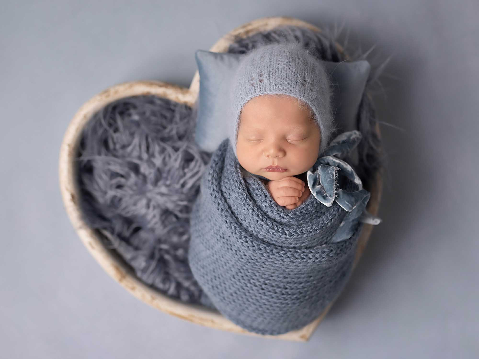 Sleeping newborn photographed in soft blue styling at Portraits by Chaya