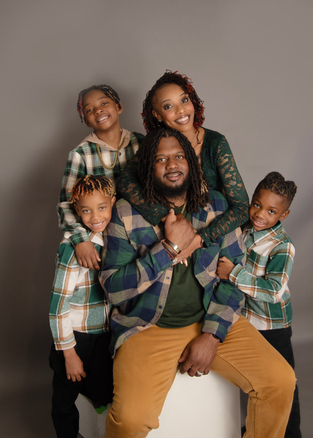 A joyful family portrait featuring a father with his three children, all smiling and wearing coordinated outfits.