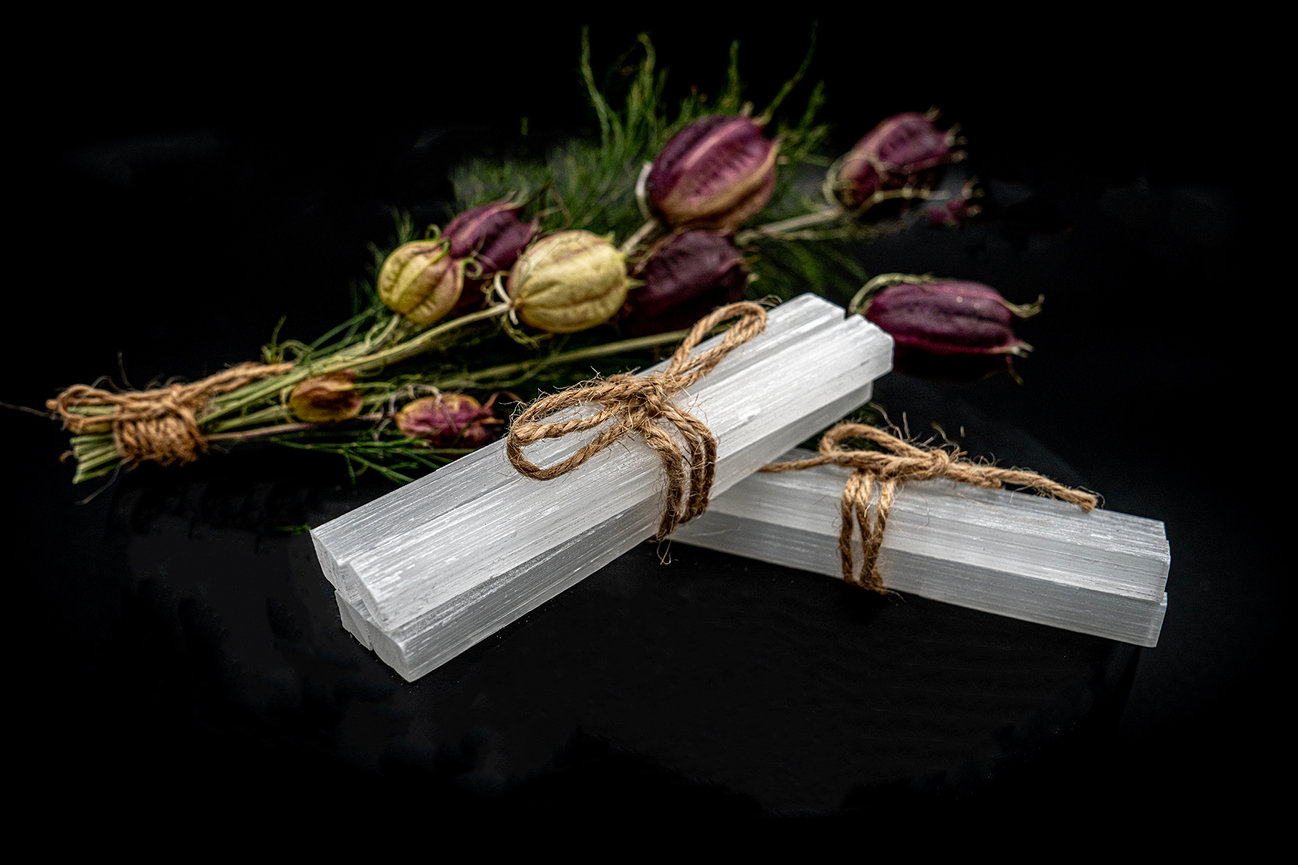 Two white salt blocks tied with twine beside decorative purple and green dried flowers on a black background