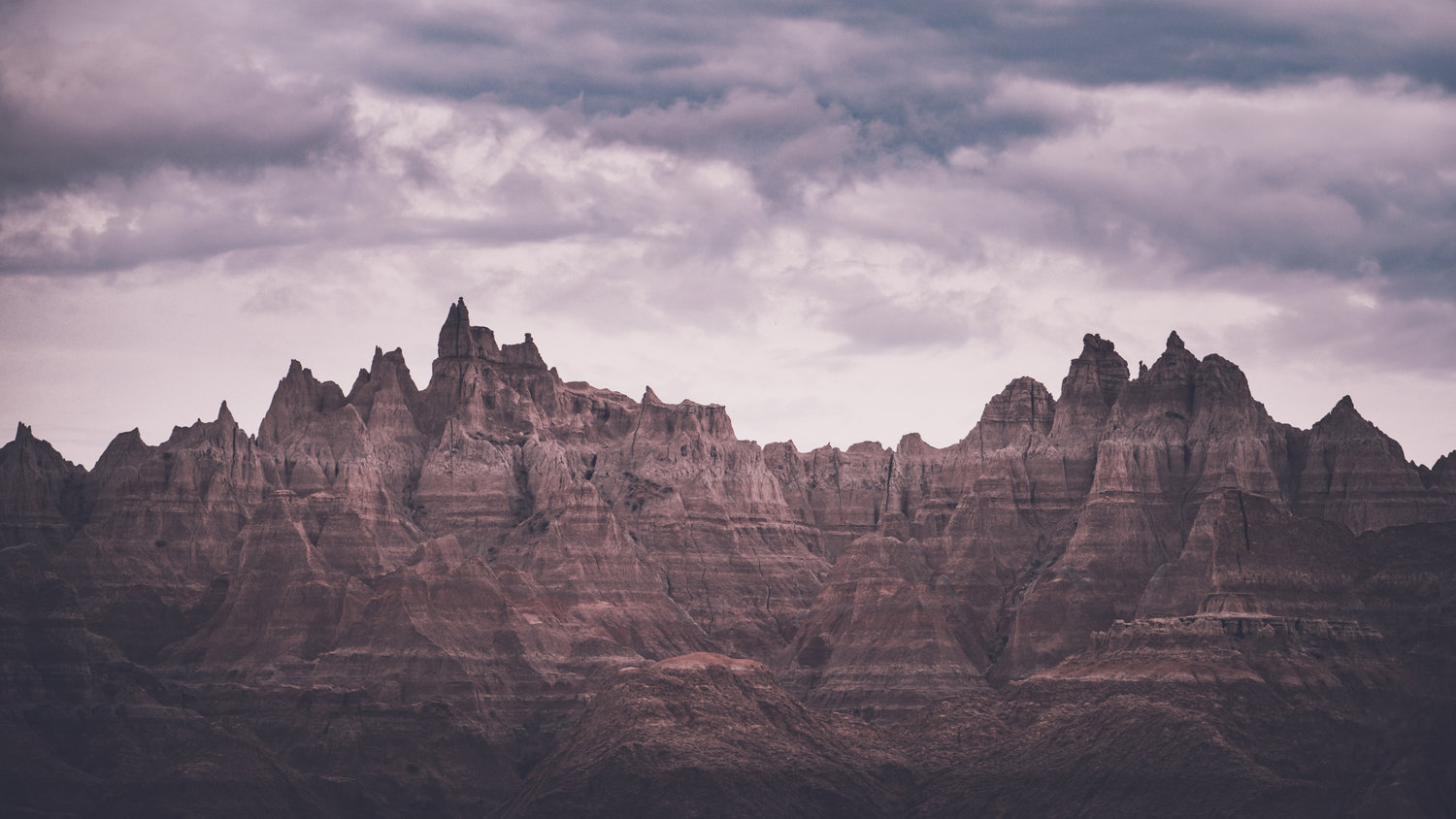 Jagged desert peaks rise under a pink and purple sky.