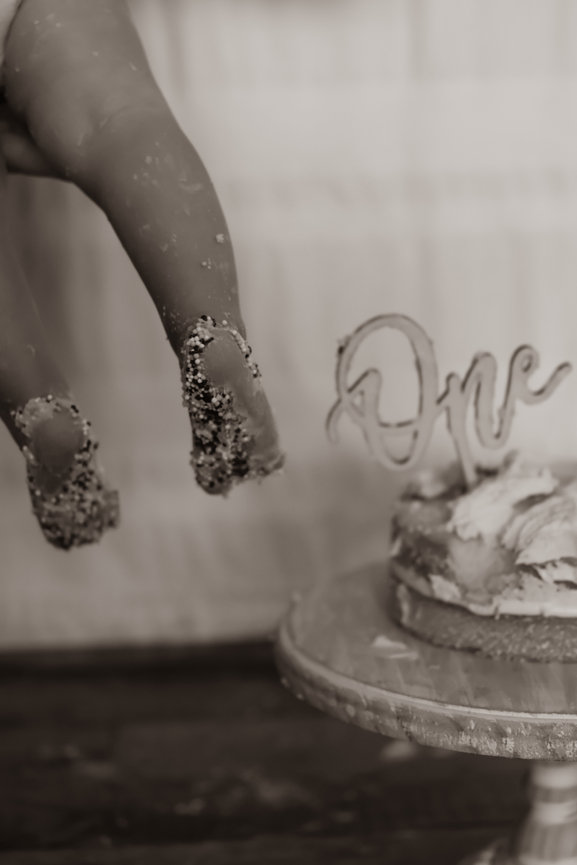 Close-up of a baby's feet beside a birthday cake topper