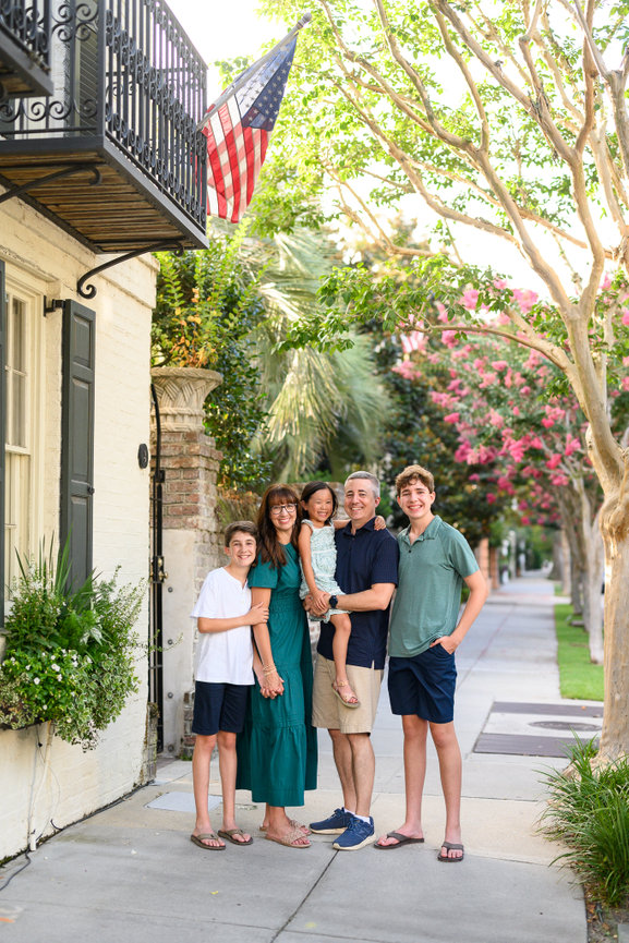 family dressed in summer shorts and tshirts on a sidewalk lined with trees and a windowbox of flowers