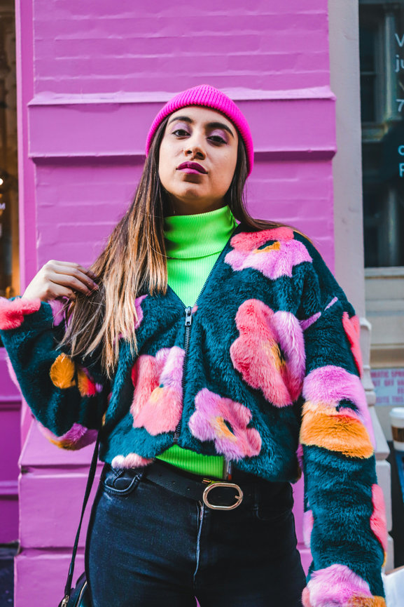 Woman in colorful jacket against pink wall