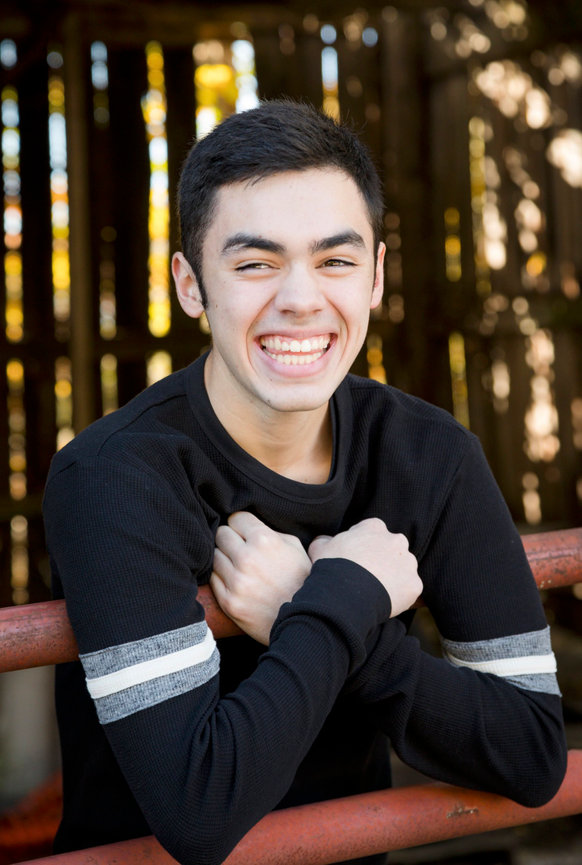 Smiling young man leaning on a red fence