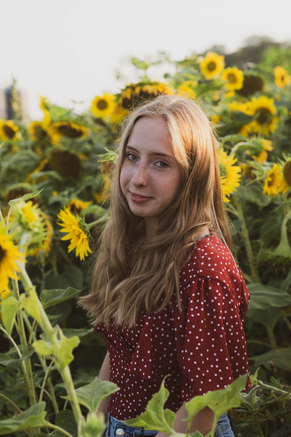 high school senior girl in a sunflower field at sunset
