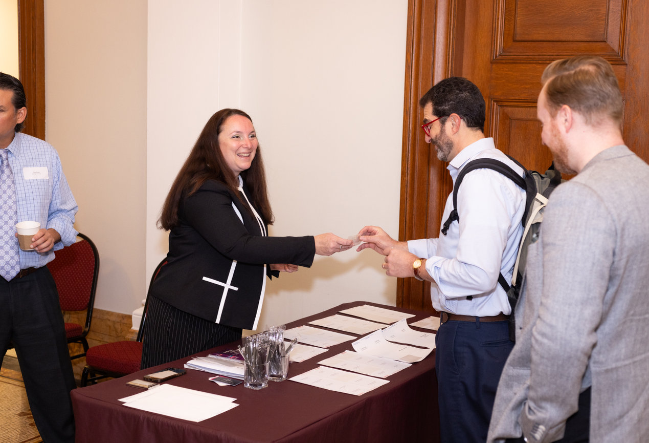 People exchanging business cards at a conference registration table.